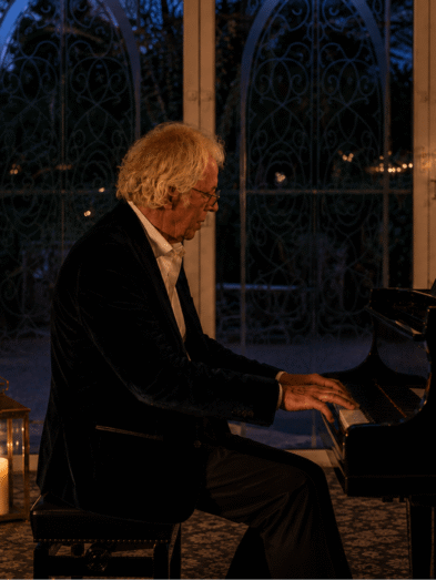 Elegant pianist performs beside candlelit grand piano in hotel lounge, offering enchanting evening ambiance.