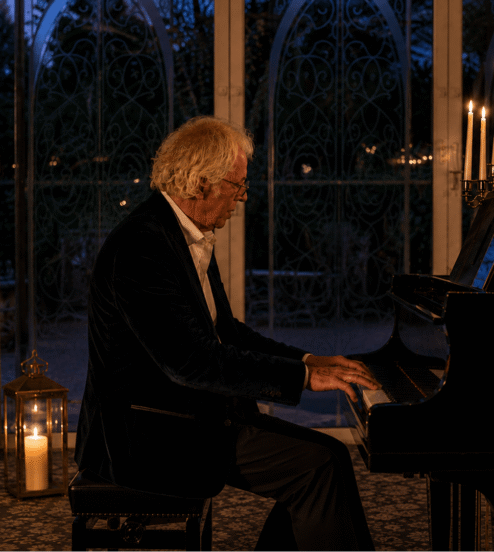 Elegant pianist performs beside candlelit grand piano in hotel lounge, offering enchanting evening ambiance.