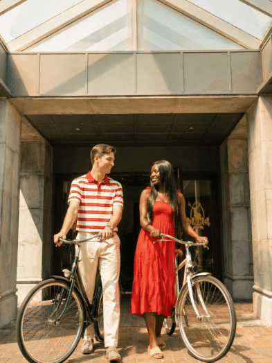 Guests enjoy cycling under a glass-roofed entrance, highlighting eco-friendly amenities and warm hospitality.