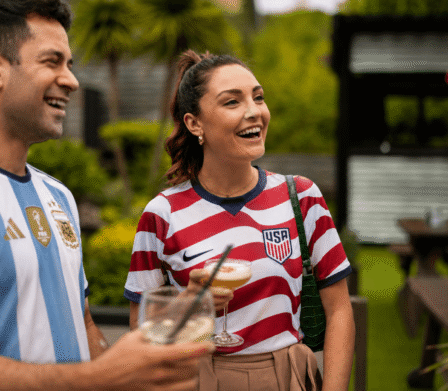 Guests enjoying cocktails and laughter in a lush hotel garden with vibrant greenery and relaxed outdoor seating.