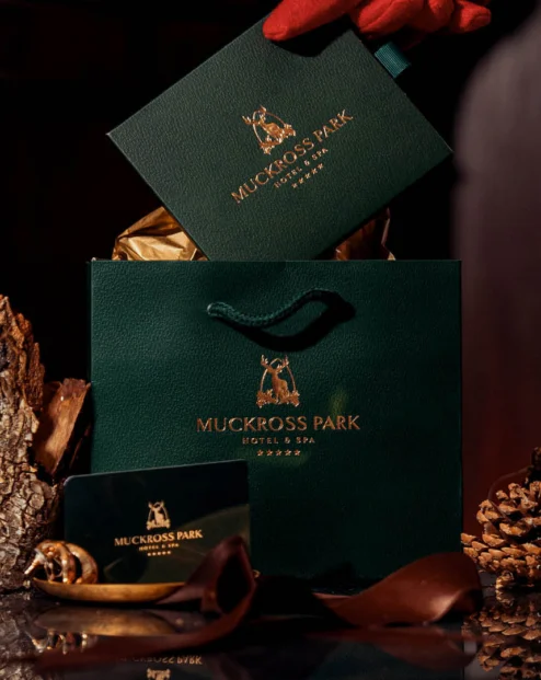 Luxurious hotel gift set with elegant bag, candle, and cosy fireplace at Muckross Park Hotel & Spa.