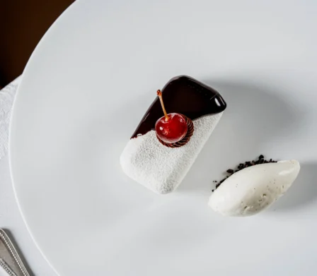 Elegant plated dessert with glossy chocolate, cherry topper and vanilla ice cream on white tablecloth, fine dining hotel restaurant